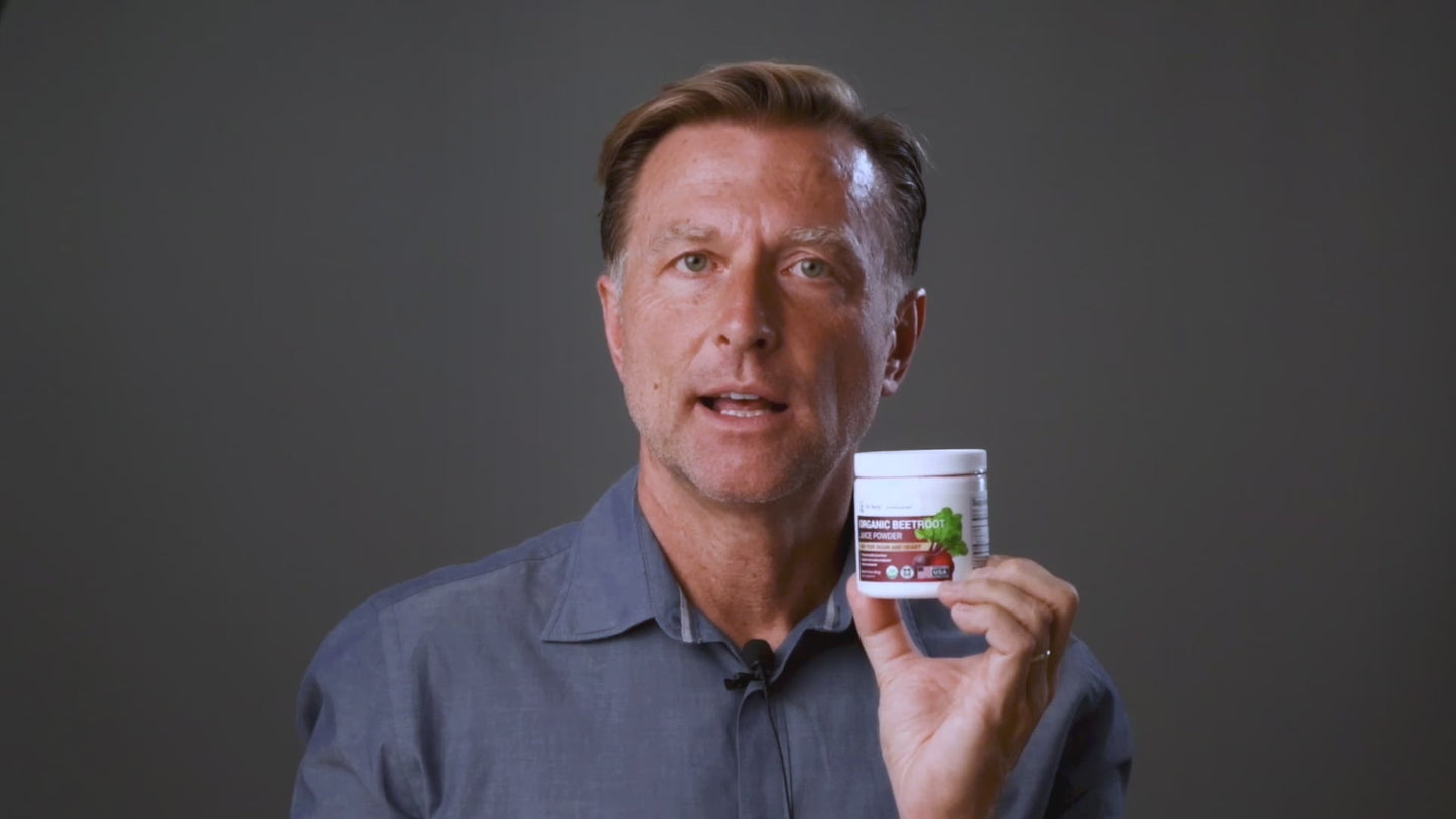 Dr Berg holds a jar of Dr Berg Organic Beetroot Juice Powder – Raw, Fresh, USDA Organic for circulation and wellness benefits.